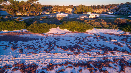 Low level drone view of a 4WD and a caravan in the  at a free camp near the beach in the Australian outback.