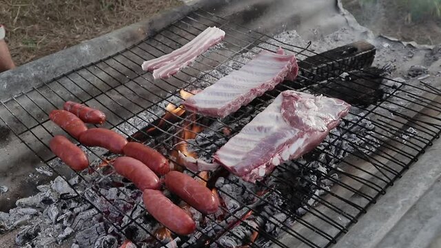 Costillas y chorizos curdos sobre una parrilla sobre fuego.
