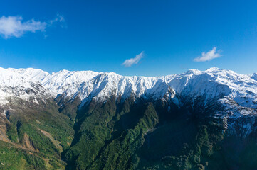 Winter mountain landscape with green slopes and snow covered peaks