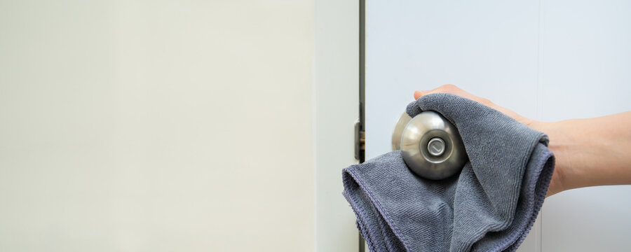 Woman House Keeper Cleaning A Dirty Stainless Door Knob In Toilet. Maid Spraying Liquid Cleaning Solution On The Dirty Door Knob Handle In Toilet And Using Micro Fabric Wipe On Door Knob Surface.