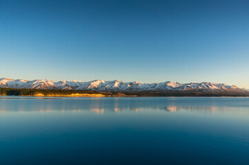 Sunrise winter mountains landscape with calm lake and water reflections