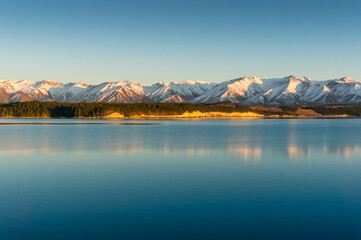 Sunrise winter mountains landscape with calm lake and water reflections