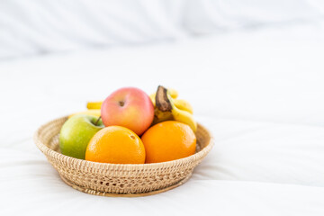 Set of seasonal fruits in the wooden basket served on the bed in the morning. Wellbeing and wellness healthy lifestyle in healthy people concept with copyspace.