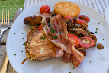 Egg toast with fried bacon stripes and halved cherry tomatoes