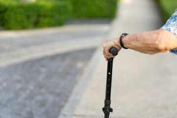 Granddaughter assist her grandmother whose age almost 90 years old exercise by walking at the park in the morning. Asian woman helping retired elder woman walking. Healthcare, wellness and wellbeing.