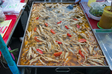 Chicken feet cooking in large dish. Unusual Asian street food