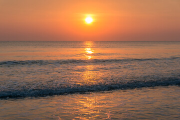 Beach sunrise landscape with orange sun and soft sea waves