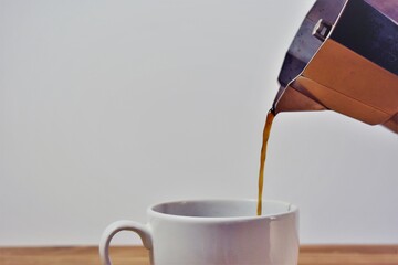 coffee pot serving coffee in a white cup