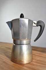 a metal coffee maker on a wood table