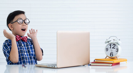 Asian boy wearing glasses excited about something on the laptop screen, something went wrong