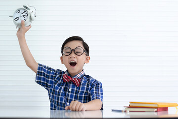 Asian boy wearing glasses and holding clock, Satisfied with the homework done in time