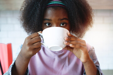 Close-up of dark skinned teenage girls drinking coffee,  looking at camera