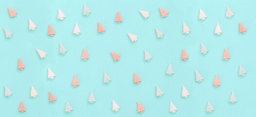 Pastel cute chocolate candies, sweets in form of Christmas trees. Banner with  New Year pattern in mint pink pastel tones on paper background minimal style. Top view.