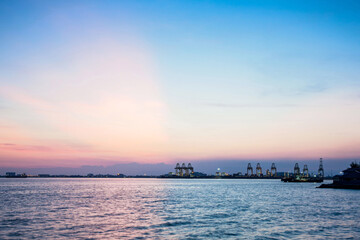 Crane for shipping container carrier with sunrise background
