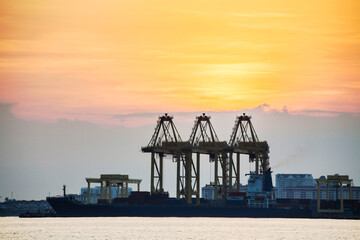 Fototapeta premium Crane for shipping container carrier with sunrise background 