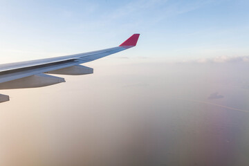 Fototapeta premium Plane wing view from inside plane in midair with blue sky cloud background