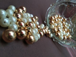 A group of golden and white pearls on pink background,costly,Golden and white glass bead