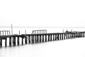 Long exposure view of wooden bridge in back and white background
