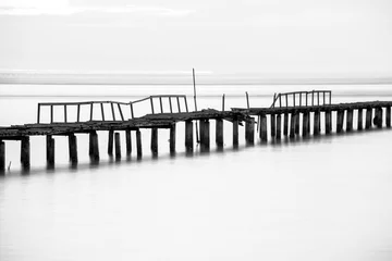 Foto auf Acrylglas Schwarz und weiss Langzeitbelichtung der Holzbrücke im Rücken und weißem Hintergrund