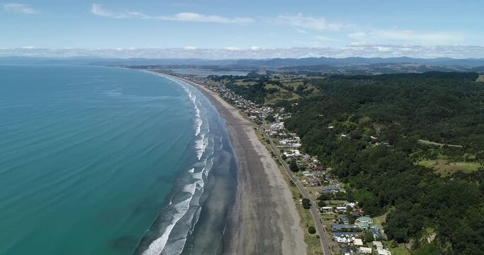 4k aerial tracking backwards motion above the popular tourist beach of Ohope Beach, known as one of the top beaches on the North Island of New zealand