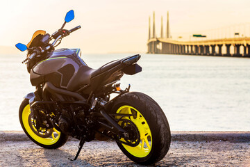 A black motorbike parking by the shore of Penang Bridge