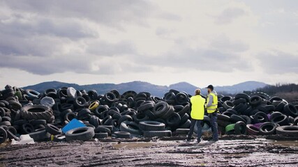 Rear view of man and woman workers on landfill, waste management and environmental concept.