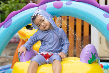 Fototapeta na wymiar Asian cute baby boy playing in inflatable baby pool.