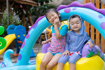 Asian children playing in inflatable baby pool.
