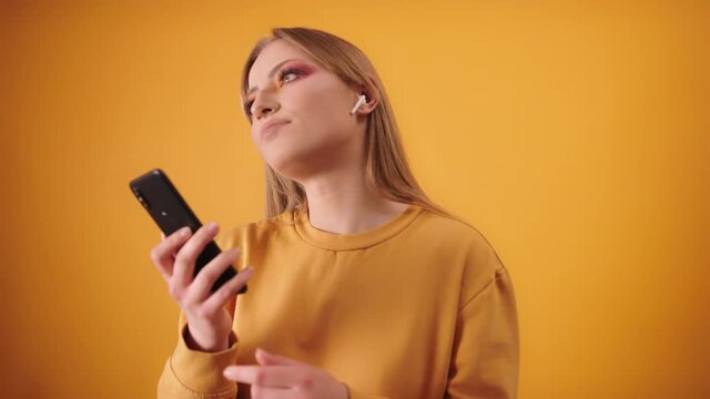 Blond Girl Listening to Music and Dancing with Wireless earphones and Smartphone