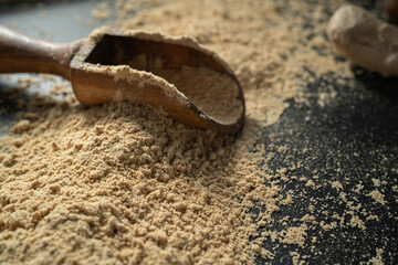 Wooden scoop on a black surface. Spice powder in the kitchen spoon.