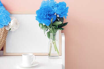 Beautiful peony flowers with cup of coffee on table in room