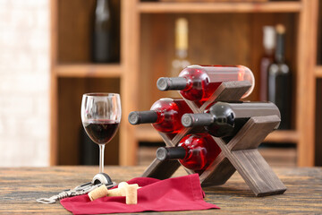 Stand with bottles of wine and glass on table in cellar