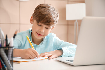 Naklejka na ściany i meble Cute little boy studying at home. Concept of online education