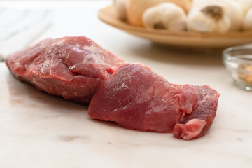 Fresh raw pork meat and some ingredients for marinade close up on a marble board on white background