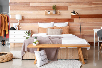 Stylish interior of room with big bed and bench