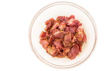 Chopped pork meat marinated with soy sauce and garlic seasoning close up in a glass bowl isolated on white background, ready to be cooked