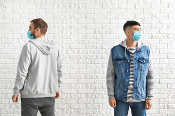 Young men wearing protective masks on white background. Concept of epidemic