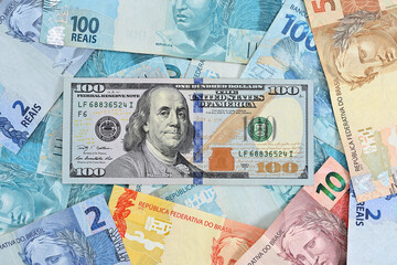 Nota de 100 dólares e notas de reais brasileiros de diversos valores