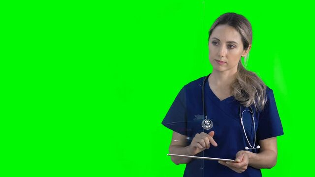 4K female nurse doctor on green screen isolated with chroma key. Woman holding digital tablet pressing buttons on virtual screen. Copy space for animation, text or image. Touchscreen gestures