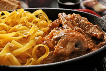 Tasty beef stroganoff with pasta on table, closeup