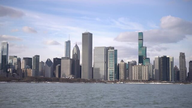 Right to left panning medium shot of the Chicago Skyline with Lake Michigan in the foreground as seen from the Museum Campus