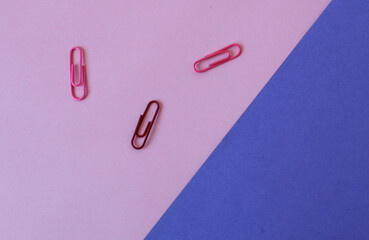 Background of pastel and purple colors with multi-colored paper clips, top view, place for the inscription-the concept of a good start to the working day.