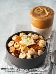 Mini pancakes cereal and dalgona coffee,gray cement background, copy space. Trendy food and drink - tiny panckakes served sprinkles, whipped instant coffee with milk or korean dalgona coffee. Vertical