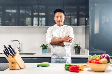 Portrait of smiling professional handsome asian man chef cooking and preparing salad with cooked food on counter standing looking at camara in the restaurant commercial kitchen