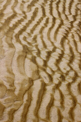 Light against dark rippled texture in beautiful golden sand on a beach
