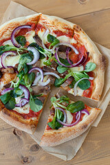 Rustic pizza with salami, mozzarella, olives and basil top view with copy space.