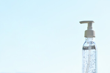 Antibacterial gel in a white transparent package with a spray against the blue sky. Concept of cleanliness and fight against coronavirus infection