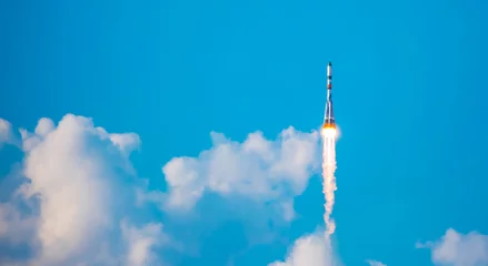Foto op Canvas Take-off of a real launch vehicle from a spaceport. A rocket takes off into the sky against a background of clouds. Startup concept, power of science and technology. © Vera