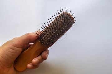 isolated people hand hold wooden comb with hair fall and loss