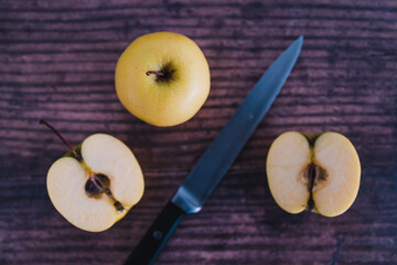 plant-based food, apple halves on wooden table next to whole apples with knife